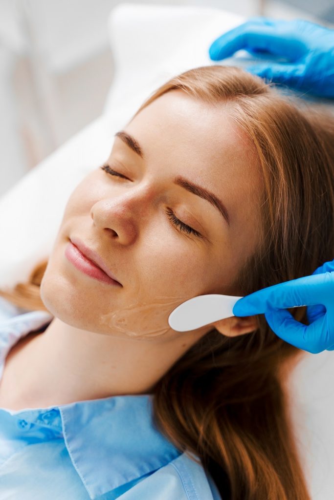 especialista realizando peeling químico facial en clínica estética