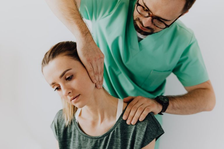 Médico explorando el cuello y el hombro de una paciente en una consulta de la Unidad del Dolor