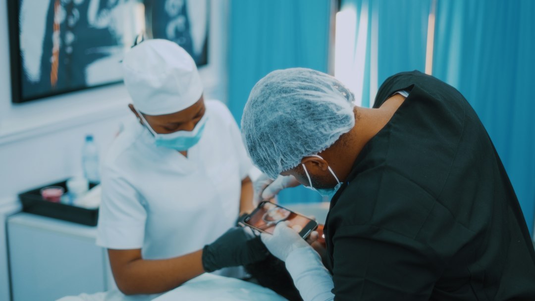 Médico explorando un bulto rojo e inflamado en la piel de un paciente en una consulta de cirugía